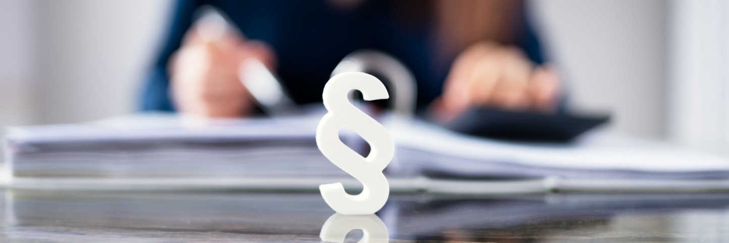 Schreibtisch mit Paragraph-Symbol im Vordergrund